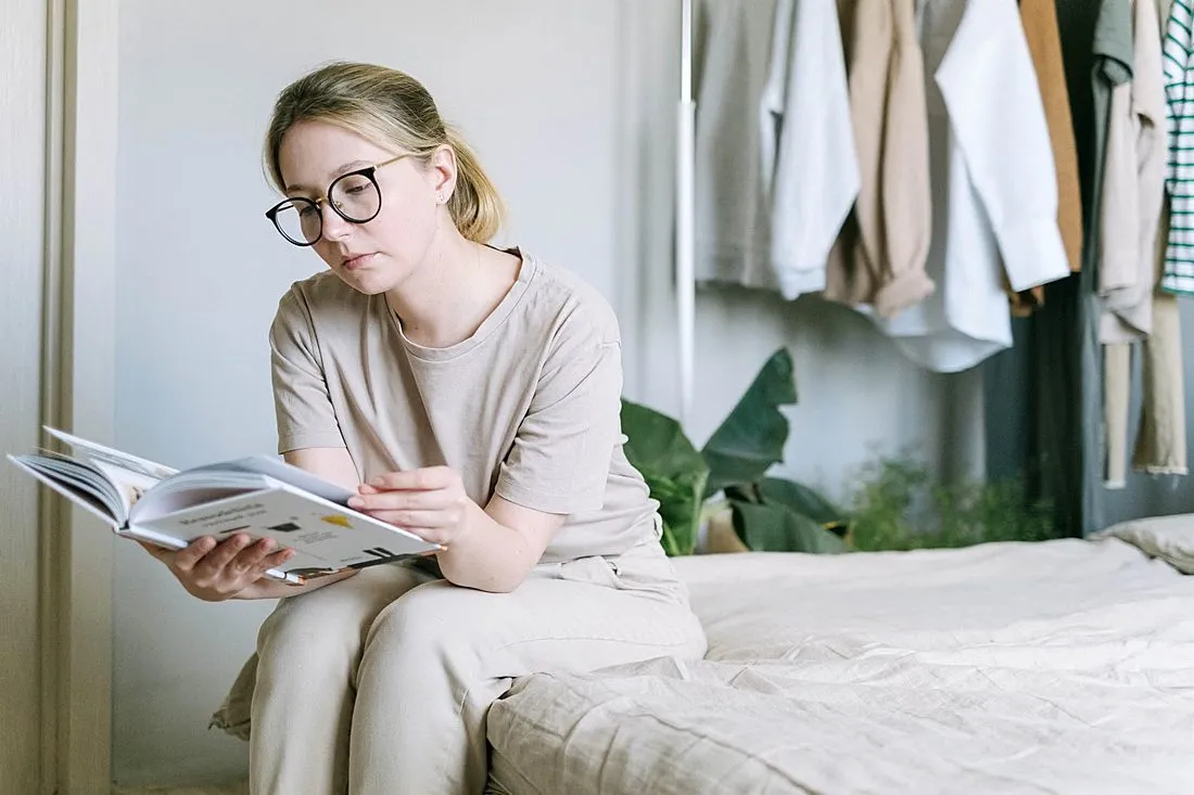 a person reading a book while wearing glasses