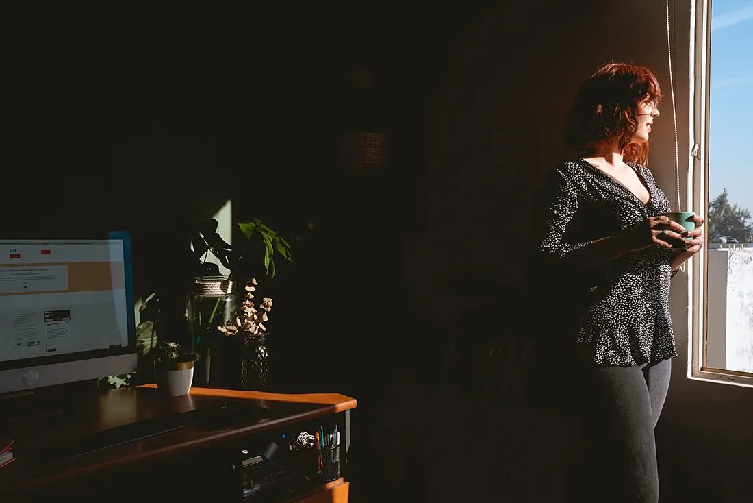 a person taking a deep breath at a desk by a window