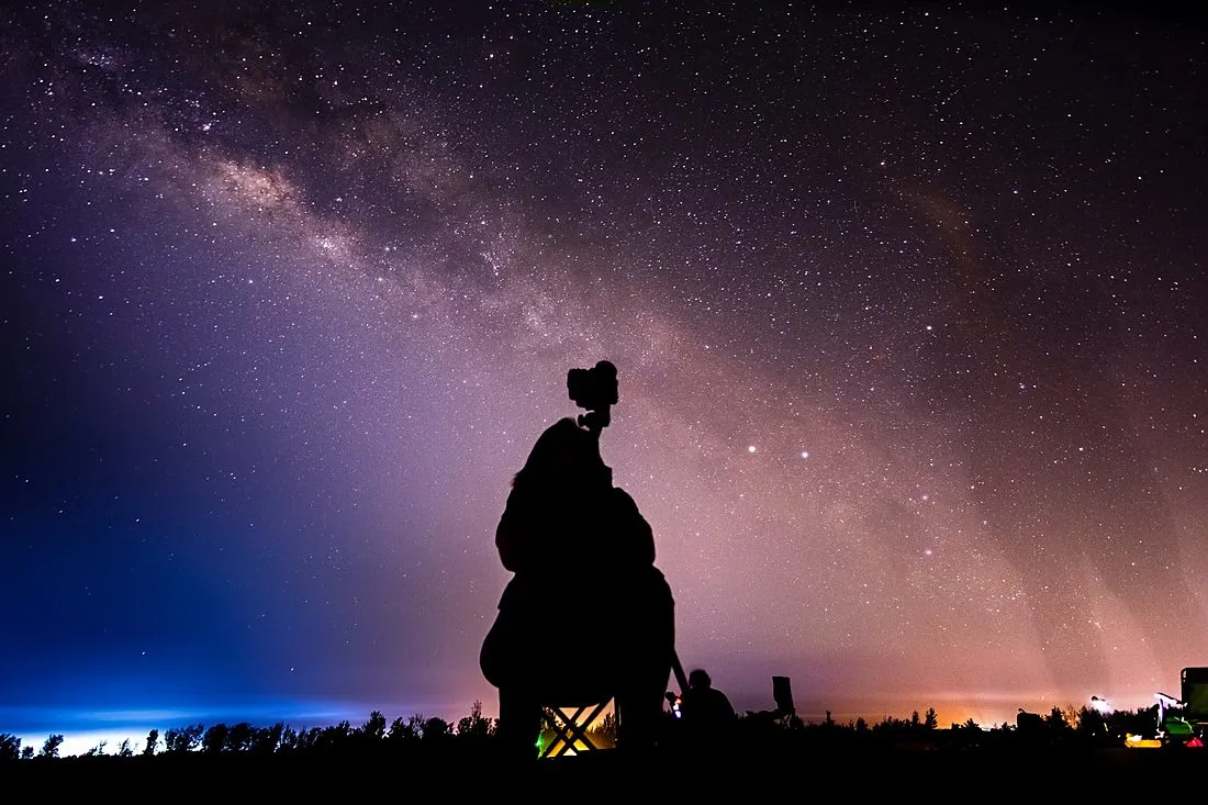an elderly astronomer looking through a telescope