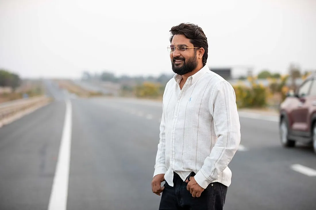 a man standing beside his car on a highway
