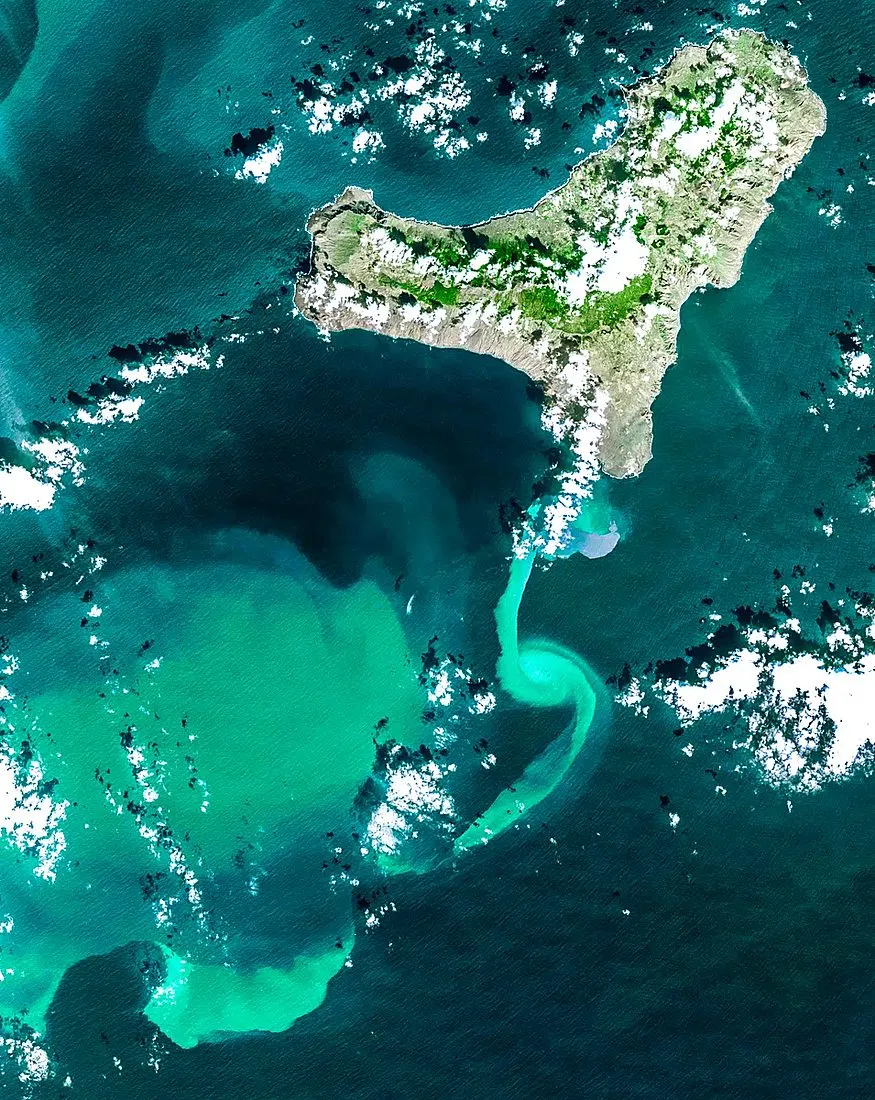an underwater volcanic eruption seen from space, with steam and ash plumes over the ocean